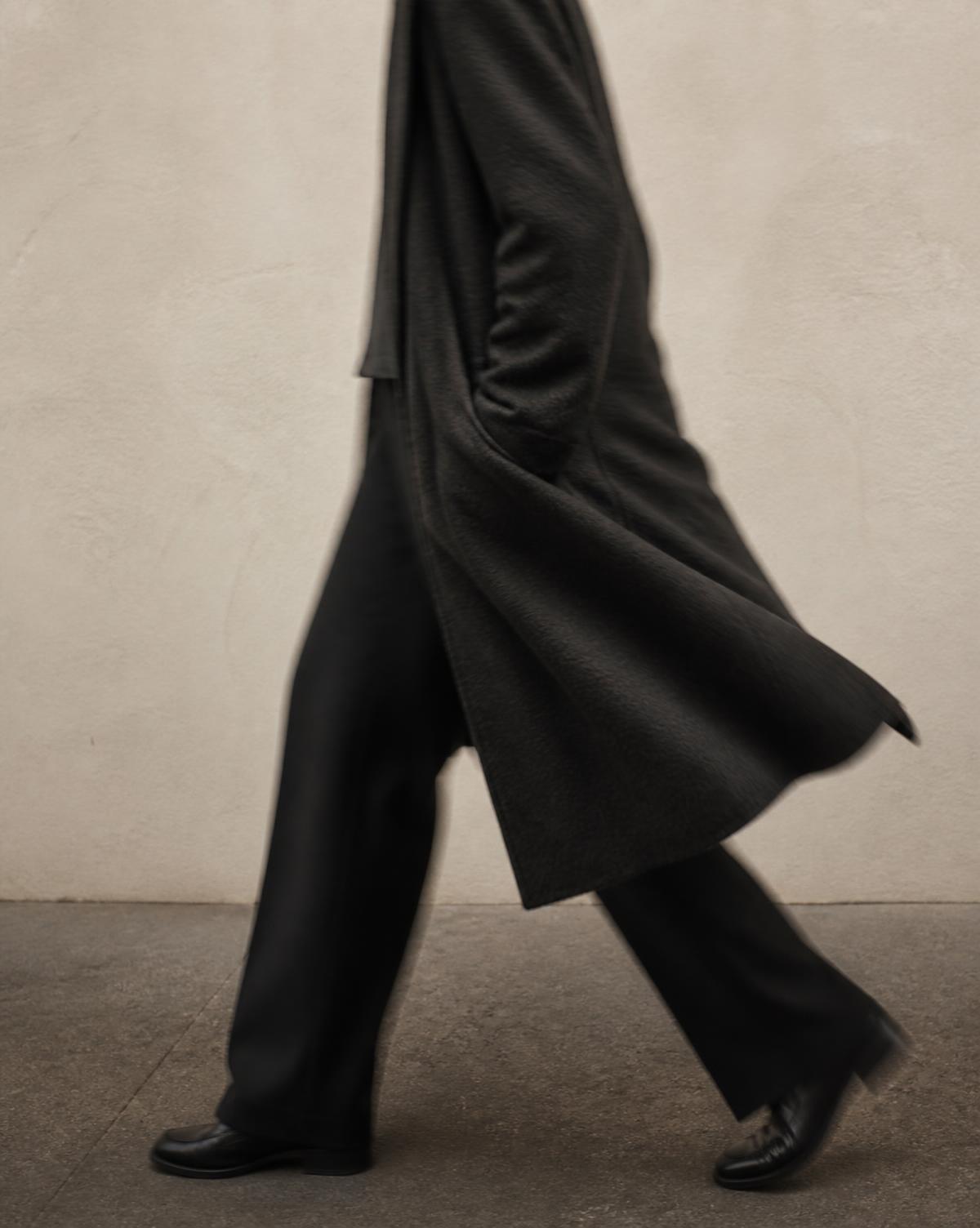 Silhouette en manteau long, cadrage éditorial en mouvement